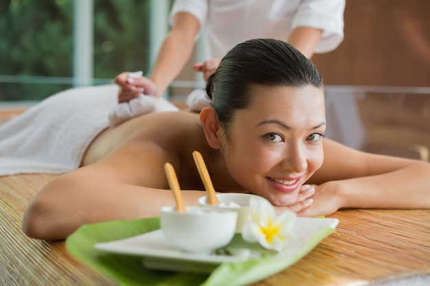 Smiling brunette getting a herbal compress massage