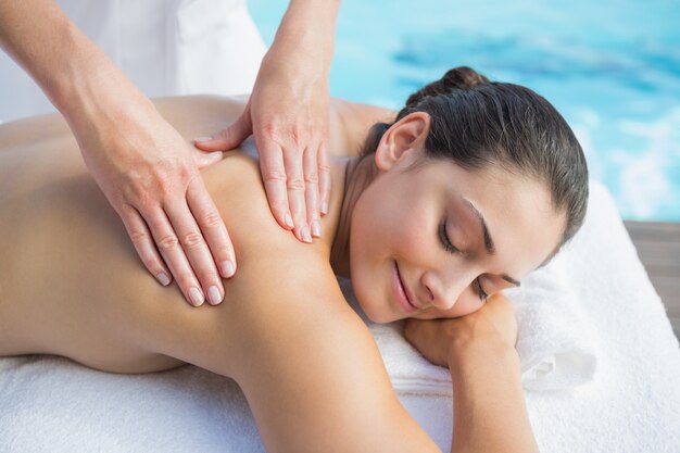 Smiling brunette getting a massage poolside