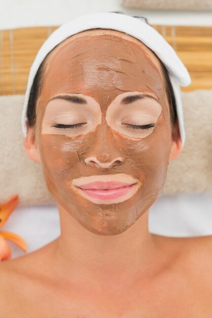 Smiling brunette getting a mud treatment facial