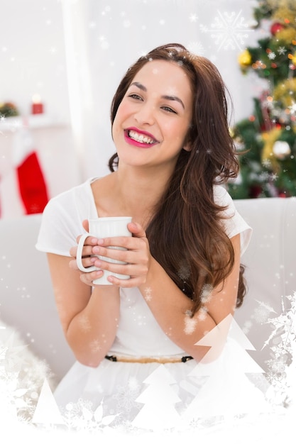 Smiling brunette holding a mug against snow falling