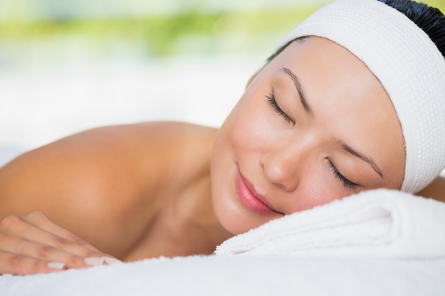 Smiling brunette lying on massage table with eyes closed