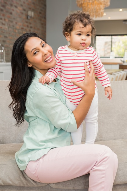 Smiling brunette playing with her baby on the sofa