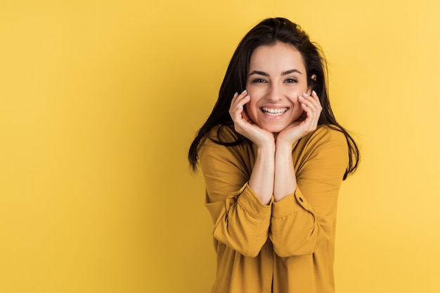 Smiling brunette posing beautifully on an yellow wall