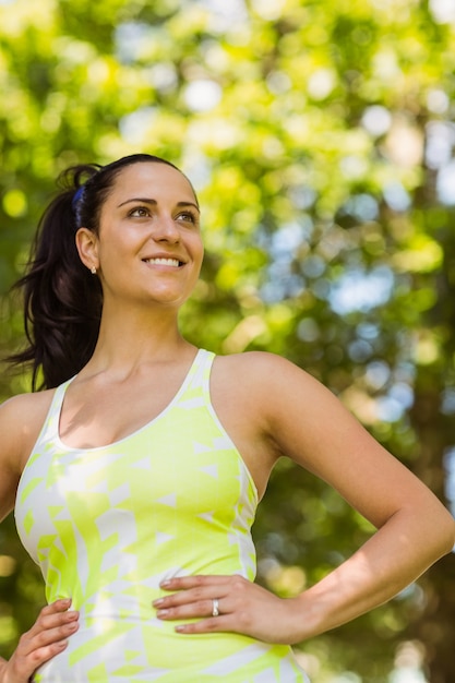 smiling brunette in sportswear with her hands on hips