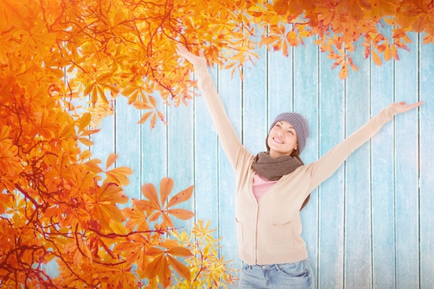 Smiling brunette standing arms open against autumn leaves pattern