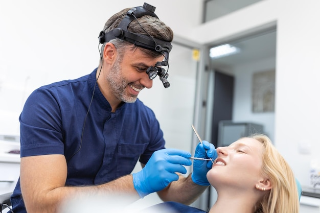 Smiling brunette woman being examined by dentist at dental clinic Hands of a doctor holding dental instruments near patient's mouth Healthy teeth and medicine concept