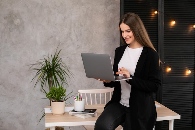 Smiling brunette woman using laptop computer over gray background. Working woman.