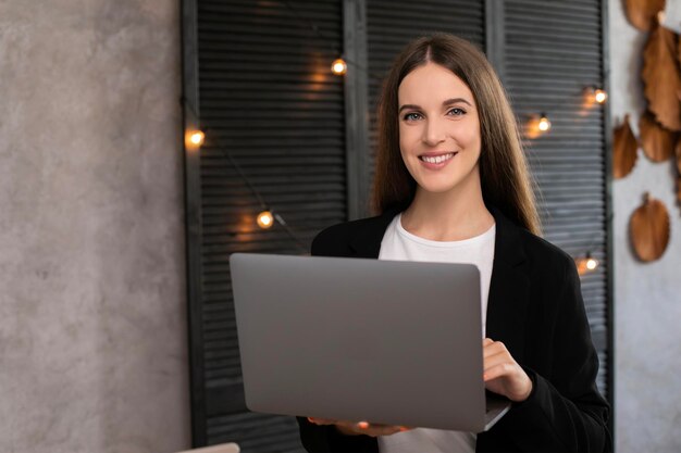 Smiling brunette woman using laptop computer over gray background