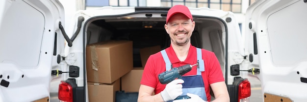 Smiling builder holding drill near car service repairman concept