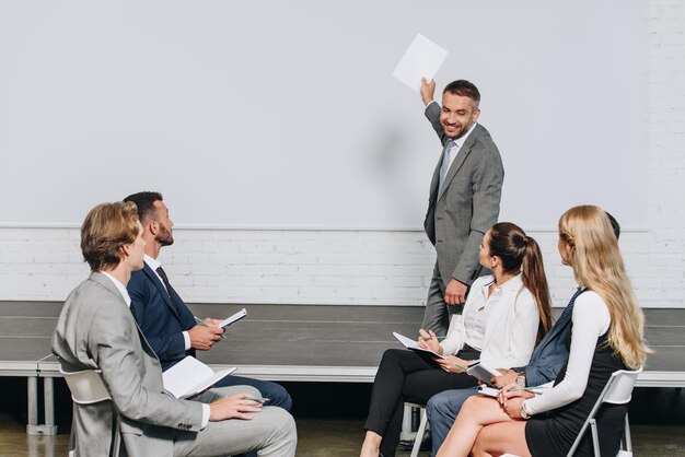 Photo smiling business coach pointing on board during training in hub