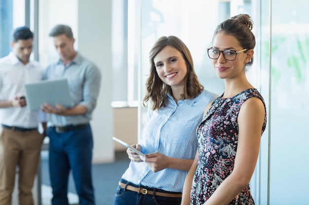 Smiling business colleagues using digital tablet in office