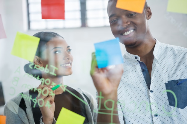 Smiling business colleagues writing on sticky notes