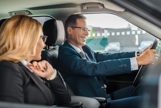 Smiling business couple sitting in new car for test drive