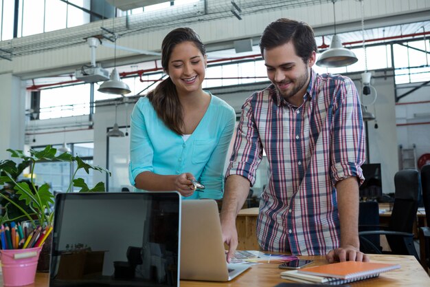 Smiling business executives discussing over laptop