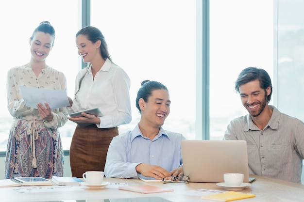 Smiling business executives discussing with each other in conference room