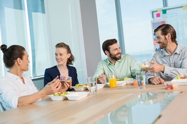 Dirigenti d'affari sorridenti che mangiano in ufficio