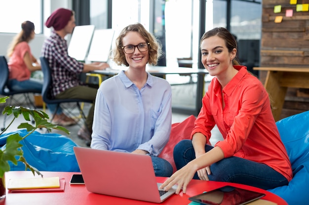 Smiling business executives sitting in office with laptop on table