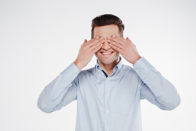 Smiling business man covering eyes of both hands