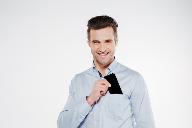 Smiling business man putting smartphone in pocket