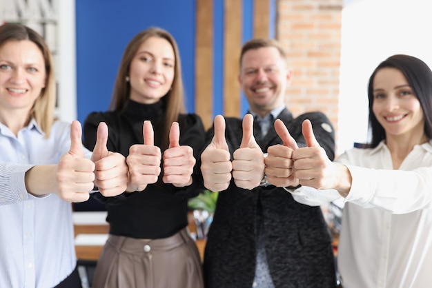 Photo smiling business people show thumbs up gesture stand in office