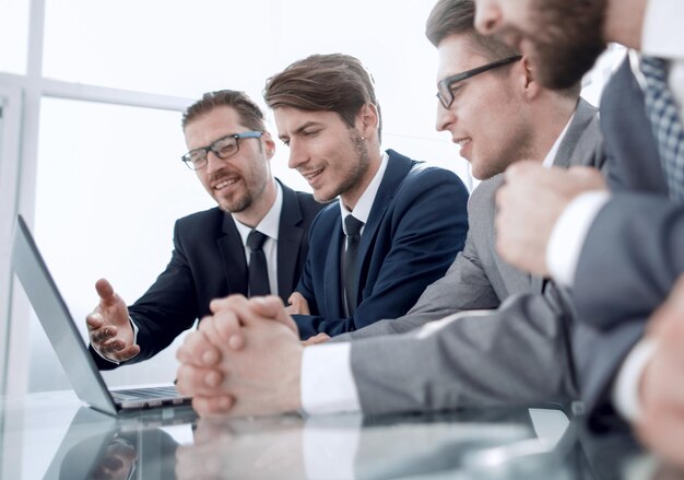 Smiling business people sitting at a desk in front of a laptop computerbusiness concept