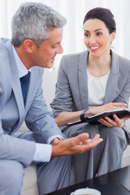 Smiling business people working and talking together on sofa