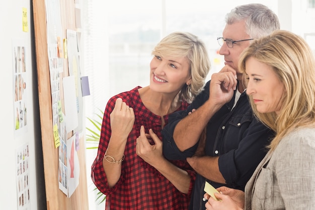 Smiling business team looking at notes on the wall