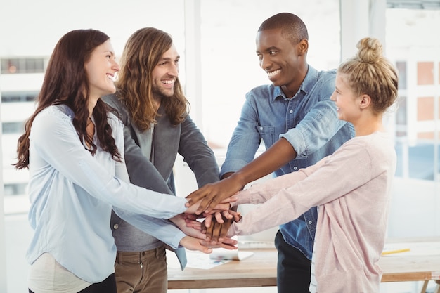 Smiling business team putting their hands together 