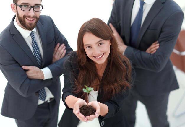 Smiling business team shows a fresh sprout