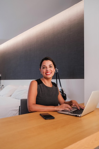 Smiling business woman after a remote meeting from her hotel room Concept teleworking