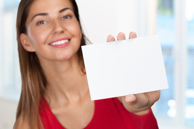 Smiling business woman handing a blank business card 