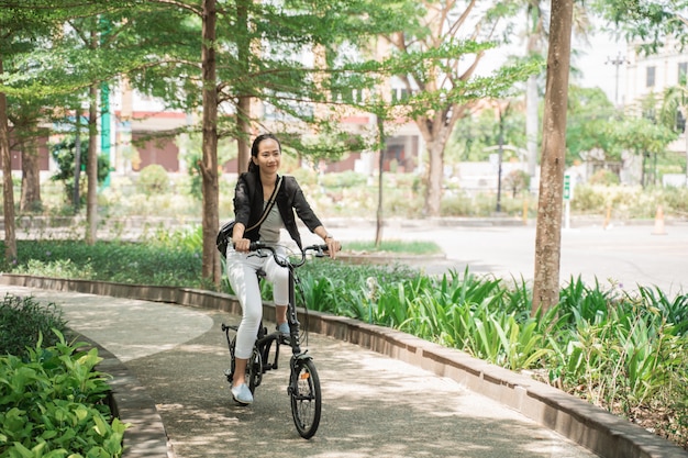 彼女の折りたたみ自転車に乗って笑顔のビジネス女性