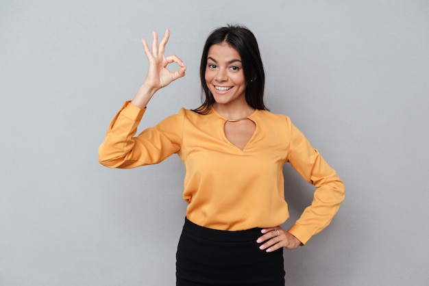 Smiling business woman showing okay gesture and looking at camera