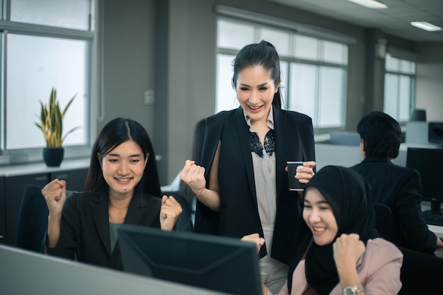 Smiling business women team working at office desk and discussing a project on computer