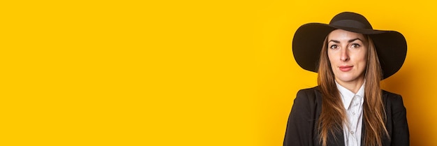 Smiling business young woman in hat and jacket on yellow background Banner