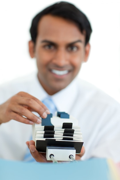 Smiling businessman consulting a business card holder