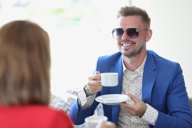 Foto uomo d'affari sorridente che beve caffè e chiacchiera con una donna nella caffetteria