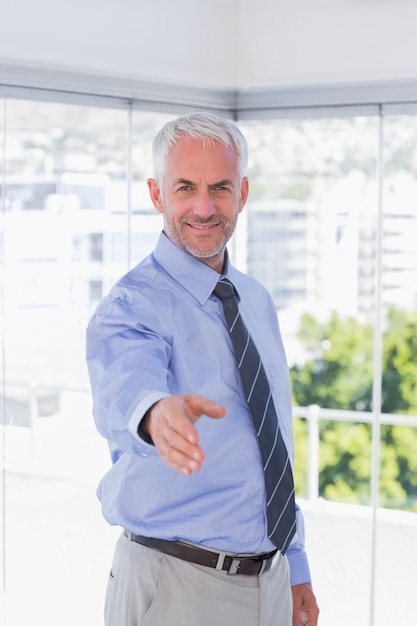 Smiling businessman extending arm for handshake