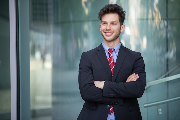 Smiling businessman in front of a blue glass background