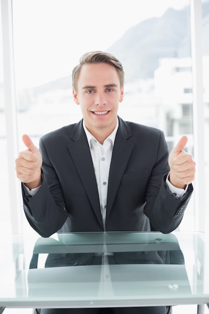 Foto uomo d'affari sorridente che gesturing i pollici su alla scrivania