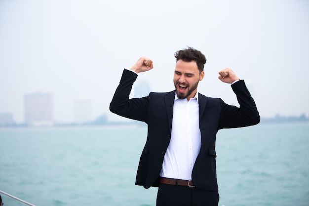 Photo smiling businessman gesturing while standing on boat at sea against sky