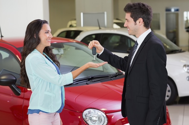 Smiling businessman giving car key to happy customer