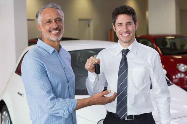 Smiling businessman giving car key to happy customer