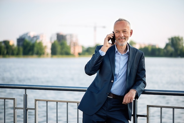 Smiling businessman in a gray suit with a smartphone.