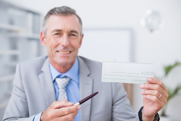 Smiling businessman holding cheque 