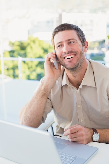 Smiling businessman making a call at his desk 