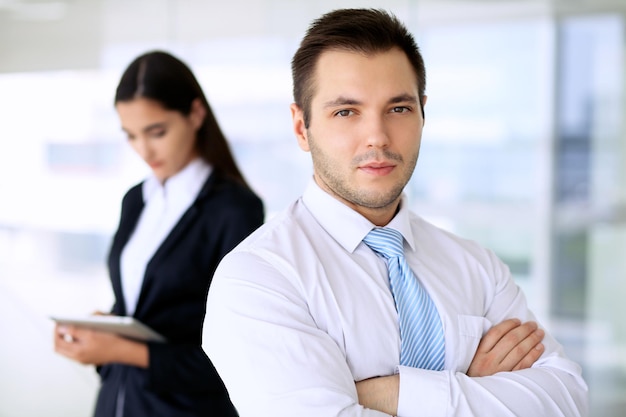 Smiling businessman in office with colleagues in the background