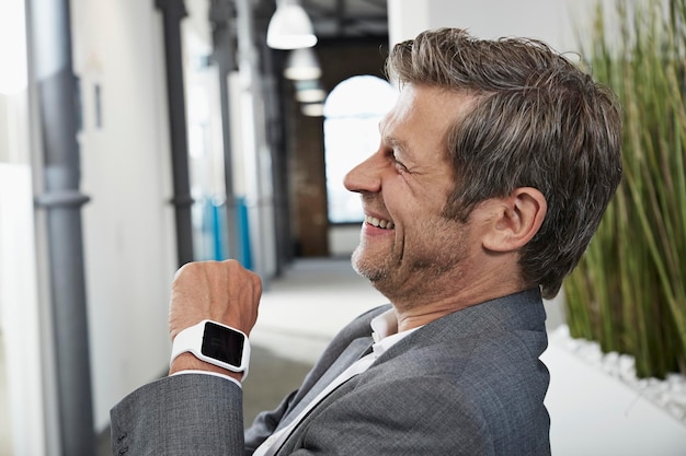 Photo smiling businessman in office with smartwatch