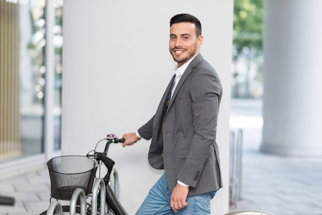 Smiling businessman parking his bicycle in front of the office