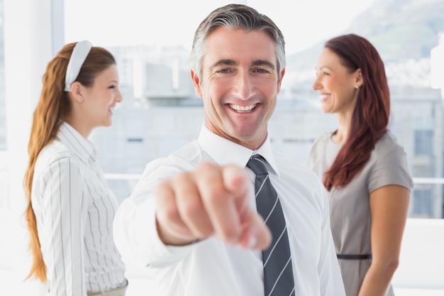 Smiling businessman pointing at camera